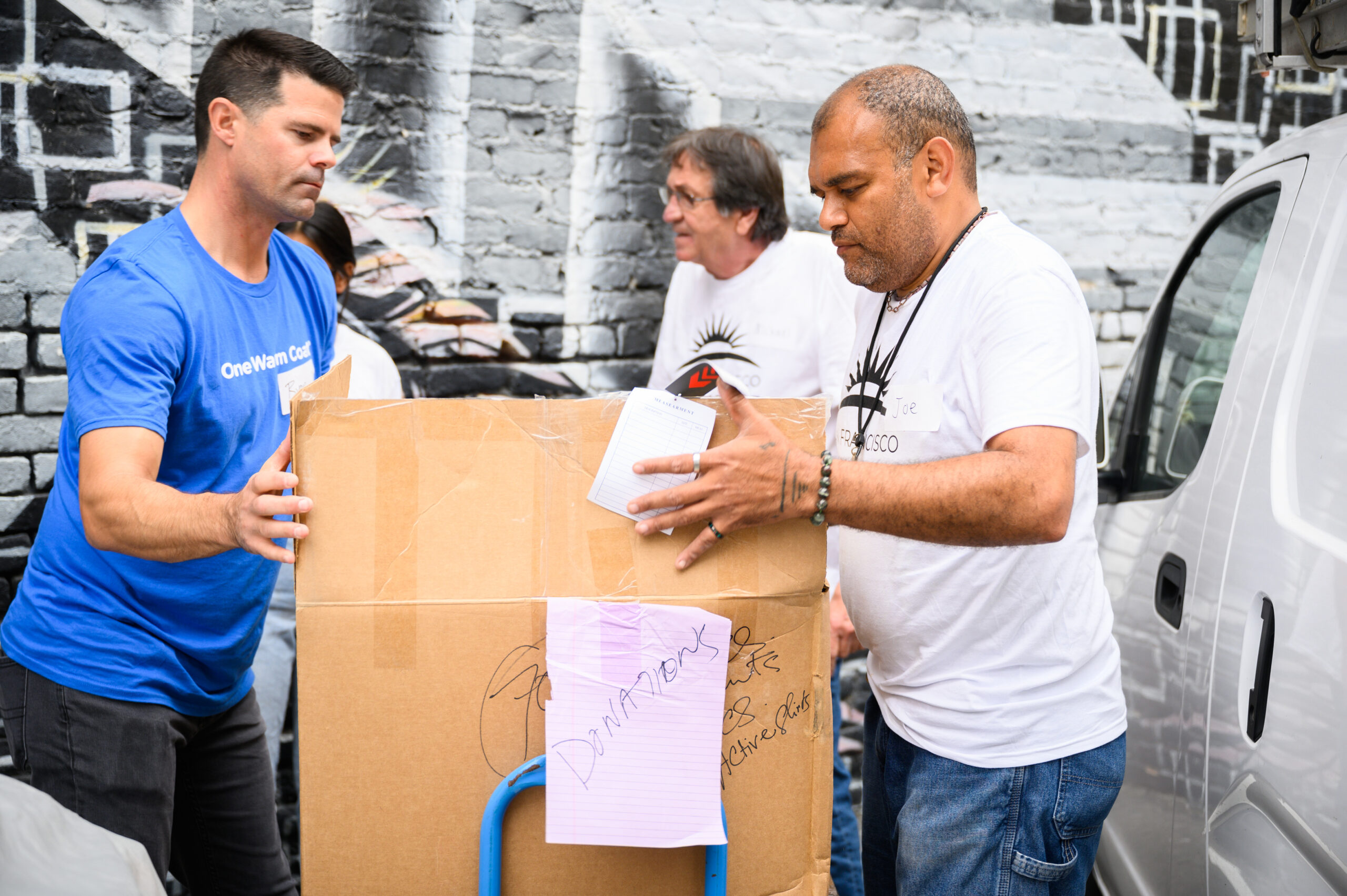 Volunteers unloading boxes of donated coats from a truck.