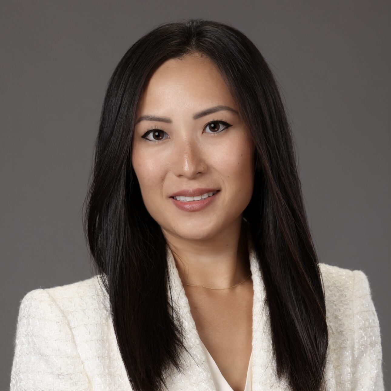 Sue Chon A woman with dark hair wears a white suite and smiles
