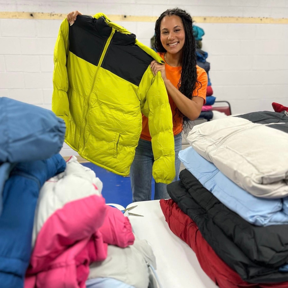 Volunteer holding a donated winter coat at a coat drive.
